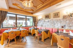 莫埃纳Monza Dolomites Hotel的一间带桌椅和石墙的餐厅