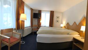 贝尔金Hotel Weisses Kreuz Bergün的酒店客房带一张大床和一把椅子
