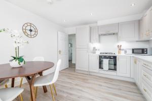 圣安德鲁斯Skye Sands - City Road Residence - Central St Andrews的厨房配有白色橱柜和木桌及椅子
