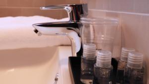 布奇纳斯科Blu Hotel的浴室水槽设有水龙头和2个玻璃瓶