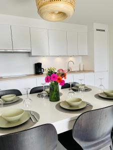 东代恩凯尔克duinpark62: gezellig 3 slaapkamer-appartement inclusief garage的白色的厨房配有桌椅和鲜花