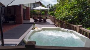 KelsoMarula Mews T17 Villa - Selborne Golf Estate的甲板上的热水浴池配有遮阳伞