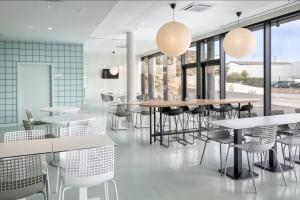 马托西纽什B&B HOTEL Porto Expo Aeroporto的餐厅设有白色的桌椅和窗户。
