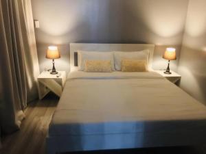 锡帕莱Angels Bed and Breakfast Sipalay City by RedDoorz的一间卧室配有一张带两盏灯的大型白色床。