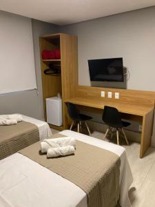 特雷西纳HOTEL CORTESE的客房设有两张床和一张书桌及一台电视。
