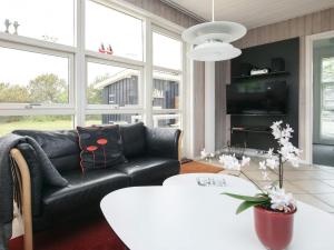伦斯楚普Holiday home Hjørring IV的客厅配有黑色真皮沙发和桌子