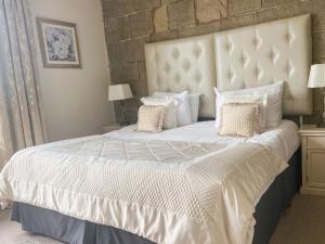 德比霍斯利山林旅舍的卧室配有一张带白色床单和枕头的大床。