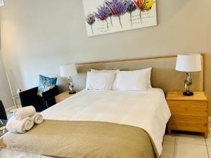 比勒陀利亚Menlyn Maine Trilogy Hotel的卧室配有一张带白色床单和枕头的大床。