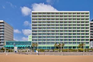弗吉尼亚海滩Holiday Inn Va Beach-Oceanside 21st St, an IHG Hotel的海滩前有棕榈树的高楼