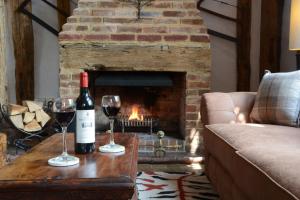 HaughleyWassicks Cottage, Haughley的客厅设有壁炉,提供两杯葡萄酒
