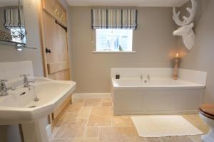 GrundisburghBird Cottage, Burgh的一间带两个盥洗盆、浴缸和卫生间的浴室