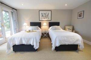 GrundisburghBird Cottage, Burgh的一间卧室配有两张带白色棉被的床