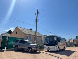 博孔巴耶沃Guesthouse Gulmira的停在房子旁边的汽车和巴士