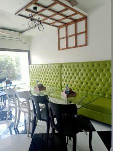 古瓦哈提VIAN INN的一间设有绿色长凳和桌椅的用餐室