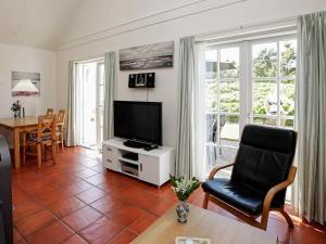 布拉万德4 person holiday home in Bl vand的客厅配有电视、椅子和桌子