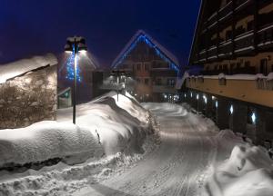 普拉托讷沃斯Borgo Stalle Residence的一座雪覆盖的街道,晚上有一座建筑