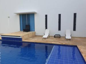 吉拉尔多特Girardot Casa estilo mediterraneo con piscina privada的一座带两把椅子的游泳池位于大楼旁