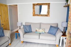 PakefieldSeagull Cottage - Suffolk Coastal Escapes的带沙发和镜子的客厅