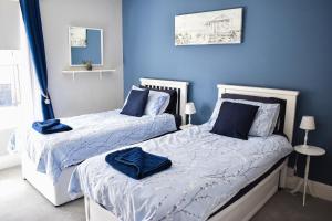 PakefieldSeagull Cottage - Suffolk Coastal Escapes的卧室设有两张床铺和蓝色的墙壁