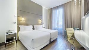 米兰NH Collection Milano Touring的酒店客房设有两张床和窗户。