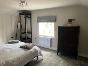 绍斯韦尔RECENTLY RENOVATED property in the heart of Southwell的一间卧室配有一张床、一个梳妆台和一扇窗户。
