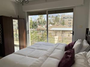 安曼Ronza Elegant Apartment的一张大床,位于带大窗户的房间里