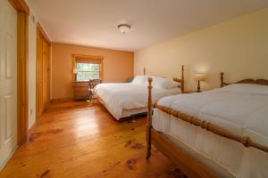 East BurkeColonial Home Directly on Kingdom Trails!的一间卧室设有两张床,铺有木地板