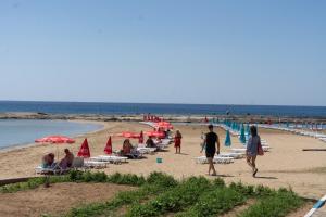 Ayia TriasLivana Hotel的一群人在海滩上,带遮阳伞