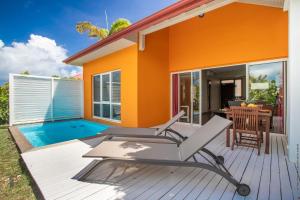 勒弗朗索瓦Les Villas du Lagon的一座带甲板和游泳池的橙色房子
