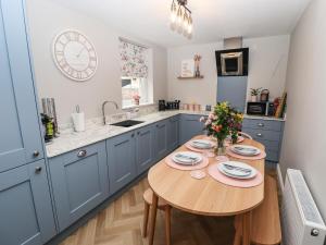 奥尔福德Printers Cottage的厨房配有蓝色橱柜和木桌