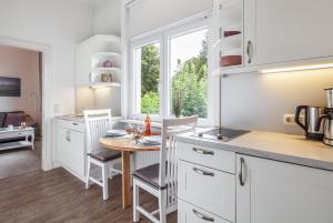 特拉弗明德Ferienwohnungen im Kapitänshaus OSTSEEROSE的厨房配有白色橱柜和桌椅