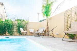 佩罗勒COSYFAMILY Piscine -WIFI- NEUF-FAMILLE -15MIN PLAGE - TOP PROS SERVICESConciergerie的一个带游泳池、椅子和棕榈树的庭院