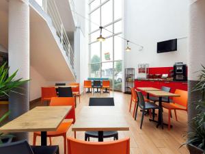 兰斯Hôtel F1 Reims Tinqueux的配有木桌和橙色椅子的餐厅