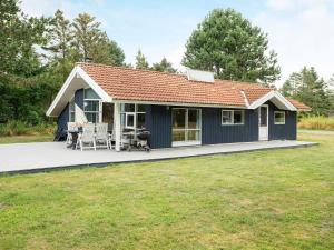 克兰尼茨Three-Bedroom Holiday home in Rødby 6的蓝色小屋 - 带甲板和草坪