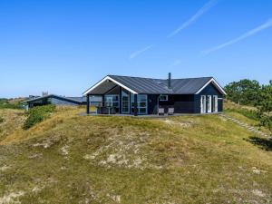 凡岛Holiday home Fanø CLXXIII的草山顶上的黑房子