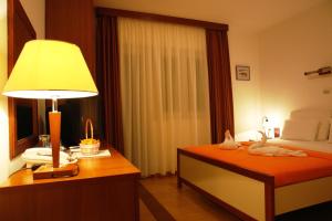 布德瓦Hotel Fineso的一间卧室配有一张床和一张桌子上的台灯
