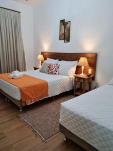 蒂拉登特斯Pousada Candelabro的一间卧室设有两张床和一张带台灯的桌子。