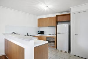 洛恩Apartment 36 Pacific Apartments的厨房配有白色冰箱和木制橱柜。
