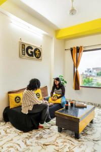 阿格拉The Hosteller Agra的两个女人坐在客厅的沙发上
