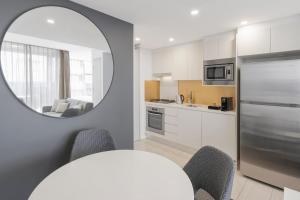 悉尼泽特兰美利通公寓式酒店的厨房配有镜子和桌椅