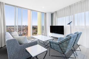 悉尼泽特兰美利通公寓式酒店的客厅配有沙发、椅子和电视
