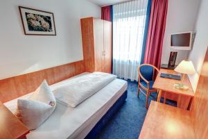 慕尼黑安塔瑞斯酒店的配有一张床和一张书桌的酒店客房