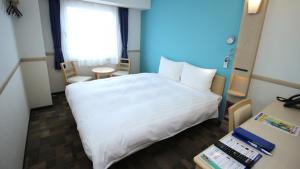 ŌtsukiToyoko Inn Fujisan Otsuki-eki的一间酒店客房,配有一张白色的床和一张书桌