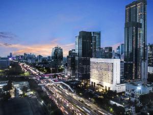 雅加达ARTOTEL Suites Mangkuluhur Jakarta的夜间城市天际线与高速公路上的交通