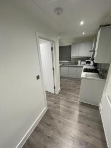 伦敦London West Ham Apartments的一间空厨房,配有白色的橱柜和木地板