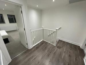 伦敦London West Ham Apartments的客房设有白色墙壁和木地板,配有楼梯
