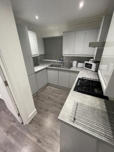 伦敦London West Ham Apartments的厨房配有白色橱柜和炉灶烤箱。