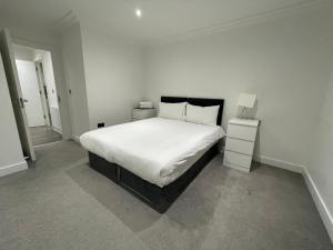 伦敦London West Ham Apartments的卧室配有白色的床和2个床头柜