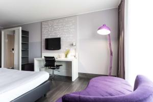 沃尔芬比特尔elaya hotel wolfenbuettel ehemals Rilano 24 7 Hotel Wolfenbüttel的一间卧室配有一张床、一张桌子和一张紫色椅子