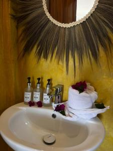 江比阿Equalia Rose hotel的浴室水槽配有三瓶肥皂和毛巾